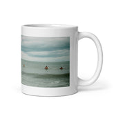 White 11oz glossy ceramic mug with a photo of surfers lined up waiting on a wave.