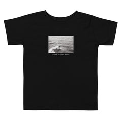 Lay flat image of children's black surf graphic t-shirt that says "Right at Your Heels" underneath the graphic. 