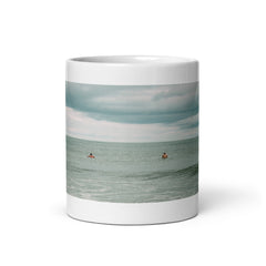 Front view of 11oz white ceramic coffee mug with an image of surfers waiting on their next wave.